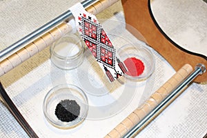 A craftswoman weaves a national beaded ornament on a loom. The traditional Ukrainian pattern adorns gerdan - a breast adornment fo