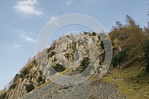 Crags and slate slag heap at the rocky, wooded summit of a mountain