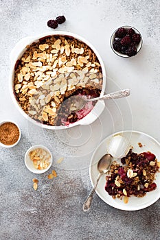 Cramble with berries, apples, almond and ball of vanilla ice cream on gray stone background