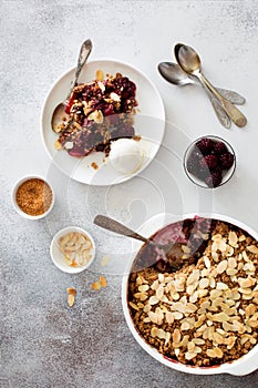 Cramble with berries, apples, almond and ball of vanilla ice cream on gray stone background