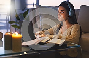 Cramming before the exam. Cropped shot of an attractive young woman working late at night in her living room at home.