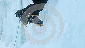 Crampons close-up on his feet ice climber on a frozen waterfall. Shards of ice.