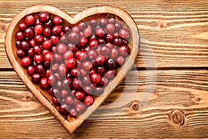Cranberries on wooden tray on brown wooden background.