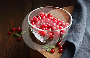 Cranberry berries in a glass bowl on wooden rustic background