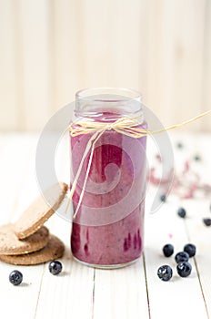Cranberry and black currant smoothie in glass jars on a white wo