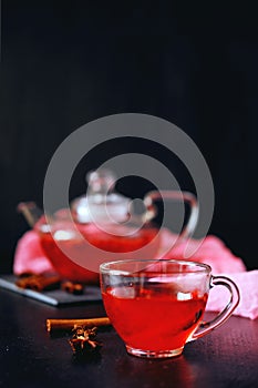 Cranberry herbal hot tea drink in glass teapot with cinnamon and