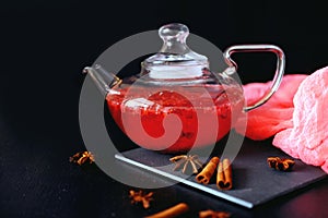 Cranberry herbal hot tea drink in glass teapot with cinnamon and