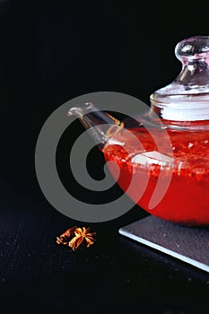 Cranberry herbal hot tea drink in glass teapot with cinnamon and