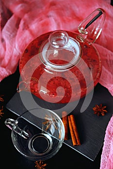 Cranberry herbal hot tea drink in glass teapot with cinnamon and