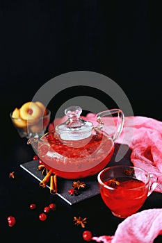 Cranberry herbal hot tea drink in glass teapot with cinnamon and