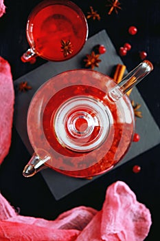 Cranberry herbal hot tea drink in glass teapot with cinnamon and