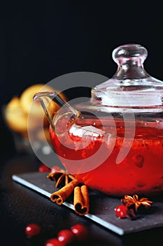 Cranberry herbal hot tea drink in glass teapot with cinnamon and