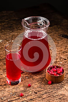 Cranberry juice in glass with fresh berry on wooden background