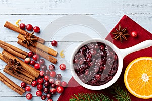 Cranberry sauce in ceramic saucepan with ingredients for cooking decorated with fir tree for Christmas or Thanksgiving day
