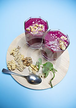 Cranberry smoothie on a blue background with slices of nuts