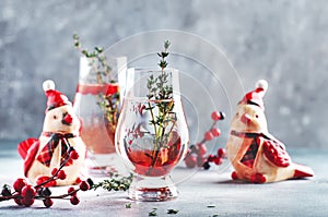 Cranberry, vodka and gin alcoholic cocktail with ice and thyme in special glass. Winter aperitif drink. Gray background. Christmas