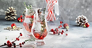 Cranberry, vodka and gin alcoholic cocktail with ice and thyme in special glass. Winter aperitif drink. Gray background. Christmas