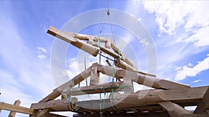 Crane above the new wooden building under construction on sunny day in the countryside area. Clip. Wooden log