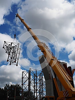 crane arm lifts iron concrete structure, construction industry