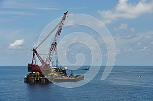 Crane barge lifting heavy cargo or heavy lift in offshore oil and gas industry. Large boat working for lift piping