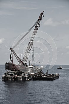 Crane barge lifting heavy cargo or heavy lift in offshore oil and gas industry. Large boat working for lift piping