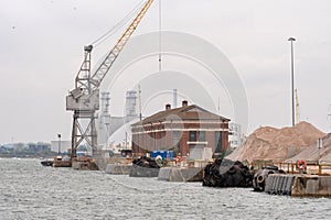 A crane, barges, warehouse and ballast at the Port of Southampton in Hampshire, UK