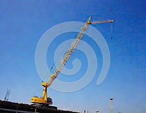 Crane and building construction site against blue sky