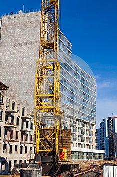 Crane and building construction site against blue sky, close-up