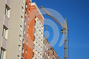 Crane and building construction site against blue sky. Unfinished building.  Extensive building, dormitory area, urban population