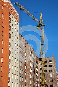 Crane and building construction site against blue sky. Unfinished building.  Extensive building, dormitory area, urban population