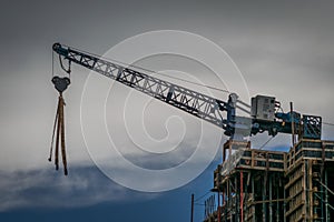 Crane in building. Gray and blue sky.