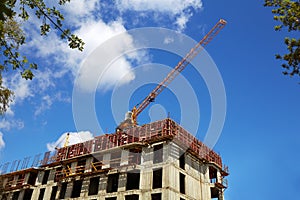 Crane on the building site. Construction of an apartment building, blue sky.