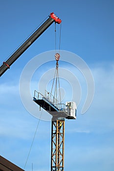 Crane and building under construction against blue sky, closeup photo Crane assembly.