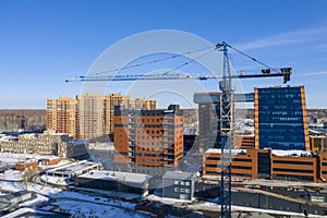 A crane among buildings under construction during the snowmelt in spring