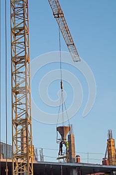Crane work. Crane on the construction lowered the concrete to workers.