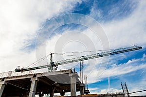 Crane on construction site on blue sky with clouds