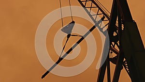 A crane at a construction site lifts a steel beam.
