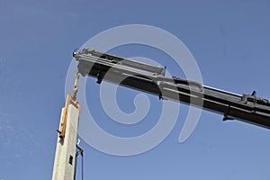 Crane. Crane lifting column for fixation with blue sky background