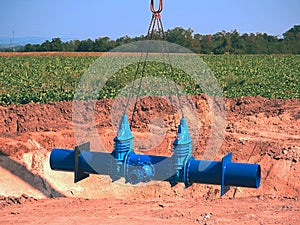 Crane handling 500mm pipe with gate valves. Construction process photo