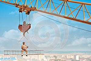 Crane holding iron construction, where sitting builder.