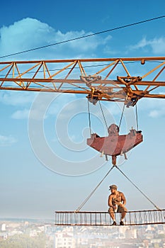 Crane holding iron construction, where sitting builder.