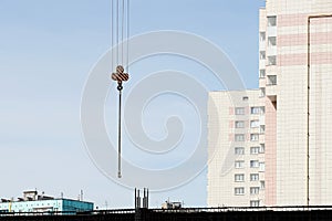 Crane hook with slings for the construction of a residential building. Blue sky, crane in the sky