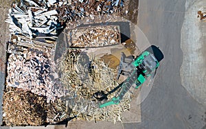 Crane with a huge claw in front of a wood scrap heap