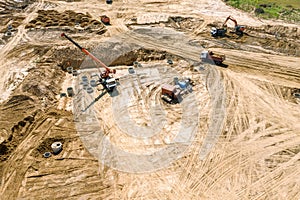 Crane installing concrete pipes of drainage system at construction site. aerial image