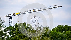 Crane jib over trees on blue sky background