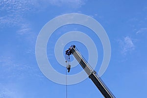 A crane lifting heavy load on blue sky background, closeup of photo