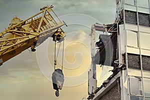 Crane lifting hook at construction site with derelict building for demolition