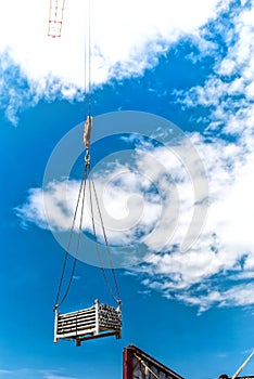 Crane lifting metalic structures of building of skyscraper. Details of construction site and tools