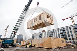 Crane lifting wooden building module in construction