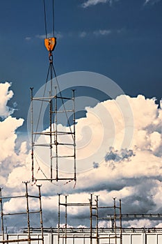 A crane lifts formwork elements at a construction site against a blue sky. Monolithic concrete works